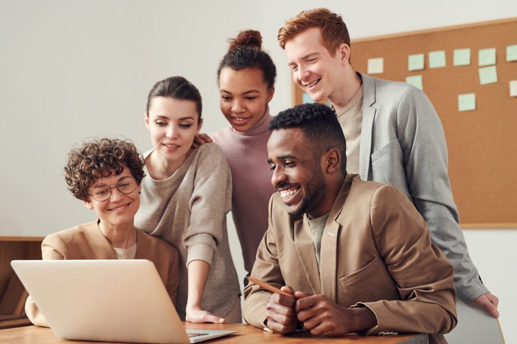 pexels photo 3182812 A group of diverse young professionals happily collaborating around a laptop indoors.